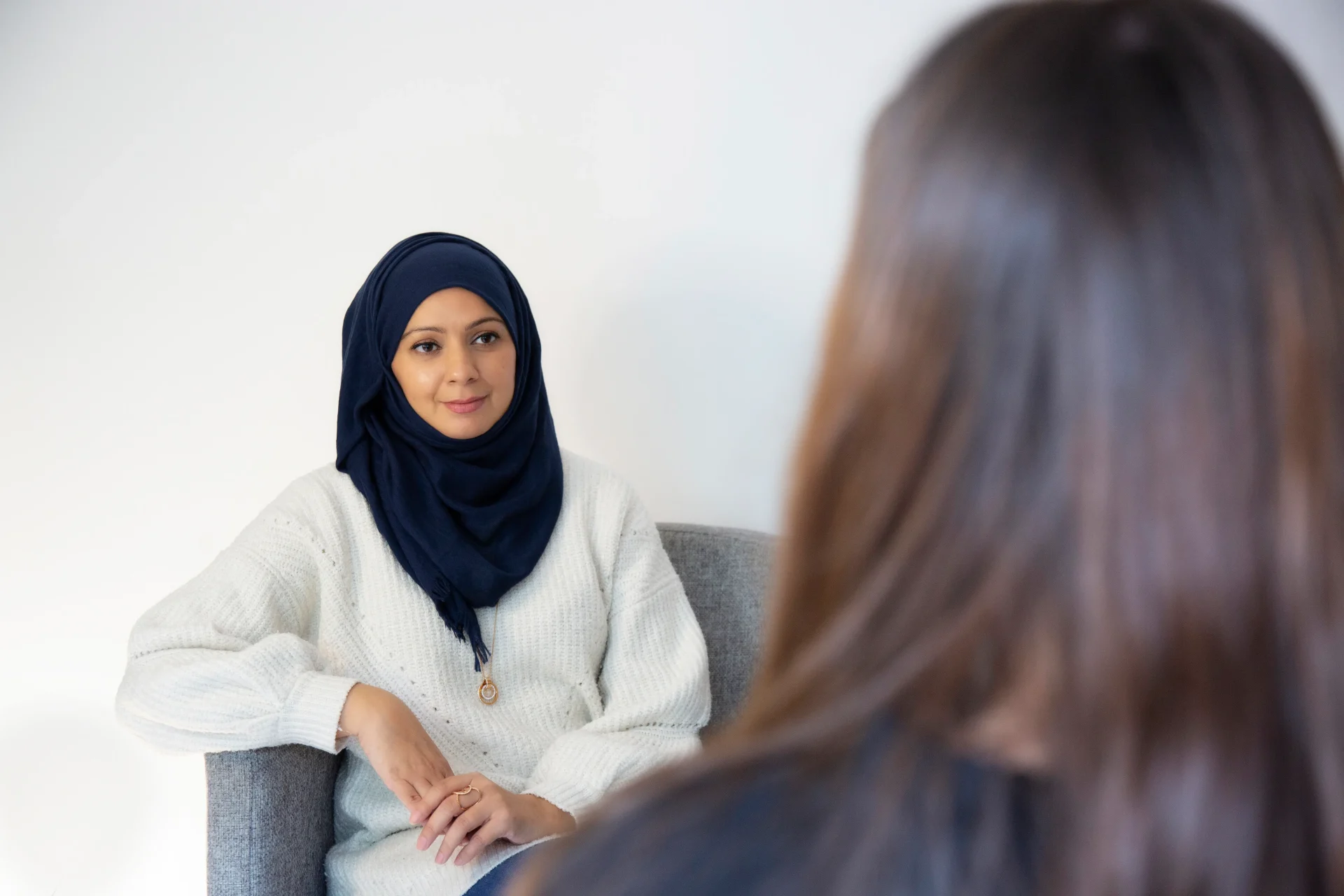 Bina72_1 Counsellor in a headscarf speaking with a client in a calm setting